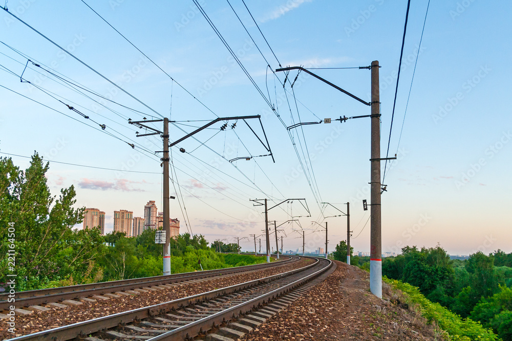 Perspective view of a railroad with power line support a background of evening sky