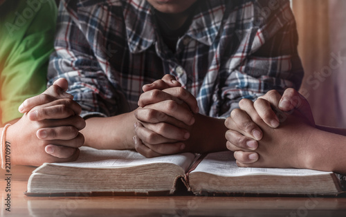 Children group praying on wooden table with open holy bible, prayer meeting concept