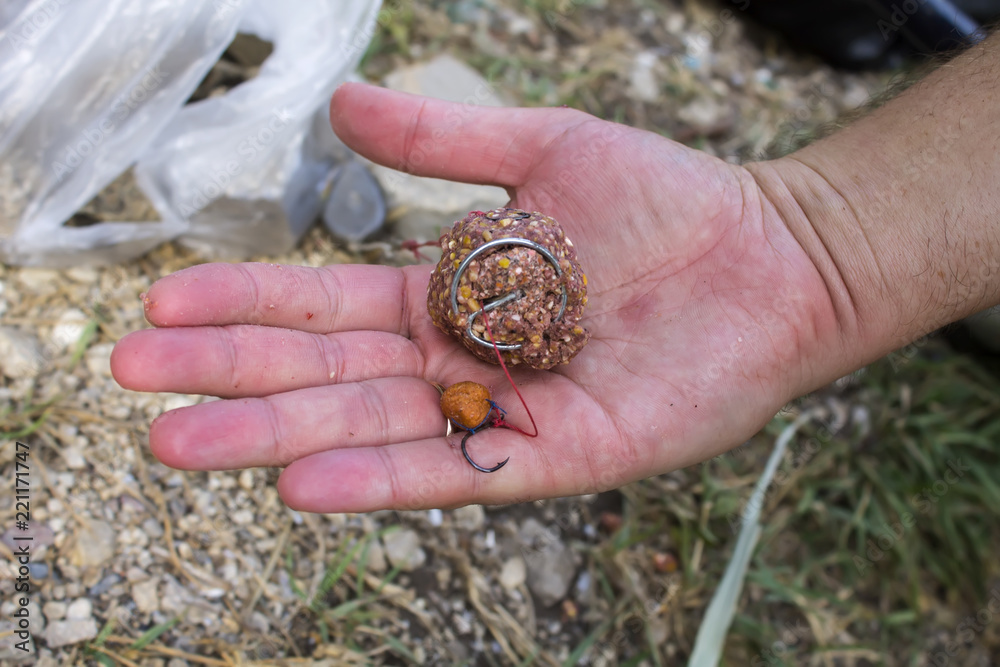  Hook for fishing with bait in the fisherman's hand close-up