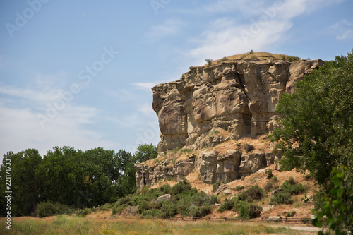 National landmark of Pompeys Pillar viewed from the front nestled between green trees in a summertime Montana landscape