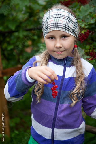 Young Caucasian girl holding red currant fresh berries in hand, looking at camera photo