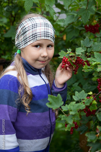 Nine years old Caucasian pretty girl with red currant fresh berries in hand, looking at camera
