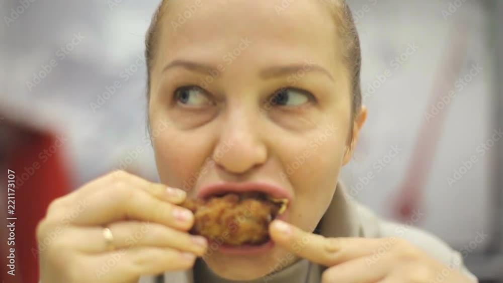 middle-aged Caucasian woman eating fried chicken in a fast food cafe. middle-aged Caucasian woman eating fried chicken in a fast food cafe.