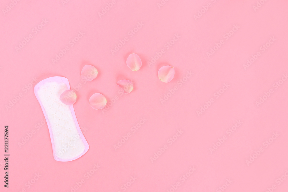 Daily sanitary pads on a pink pastel background with rose petals. The concept of ease, security, femininity.