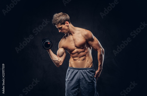 Handsome shirtless man with stylish hair and muscular ectomorph body doing the exercises with dumbbells. © Fxquadro