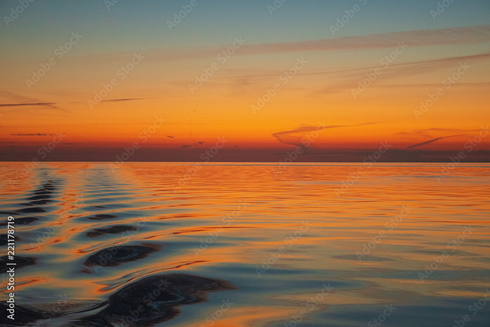 Ocean sunset, shot mid  ocean on an exceptionally calm day. The wake of the yacht rippling out.  