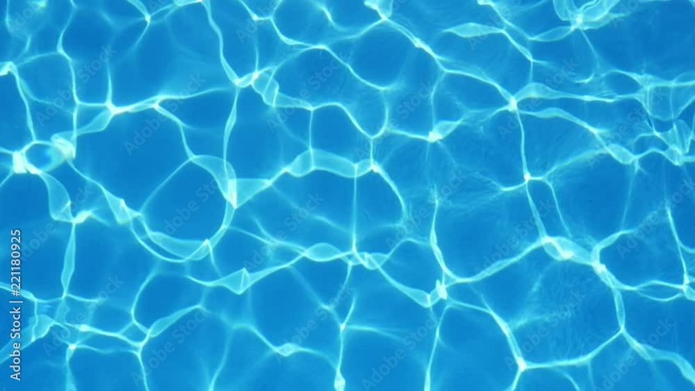 An amazing view of swaying turquiose waters in a modern swimming pool with shimmering curvy lines making a cheerful and arty background. 