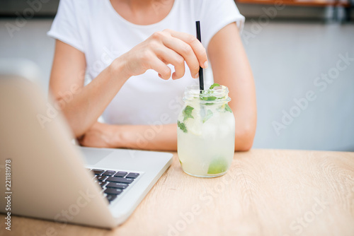 Woman with lemonade and laptop in cafe. Copy space.
