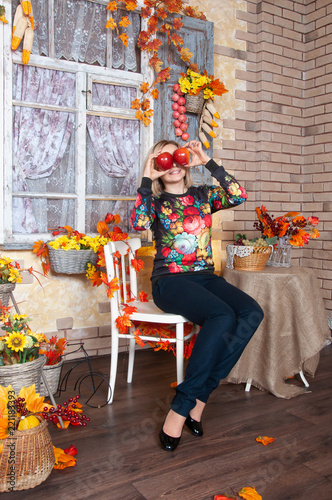Happy woman smiling and playing with red apples at home in autumn decoration. Happy woman enjoying the autumn.