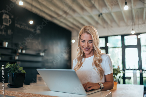 Smiling stylish blonde woman using laptop indoors. © bnenin