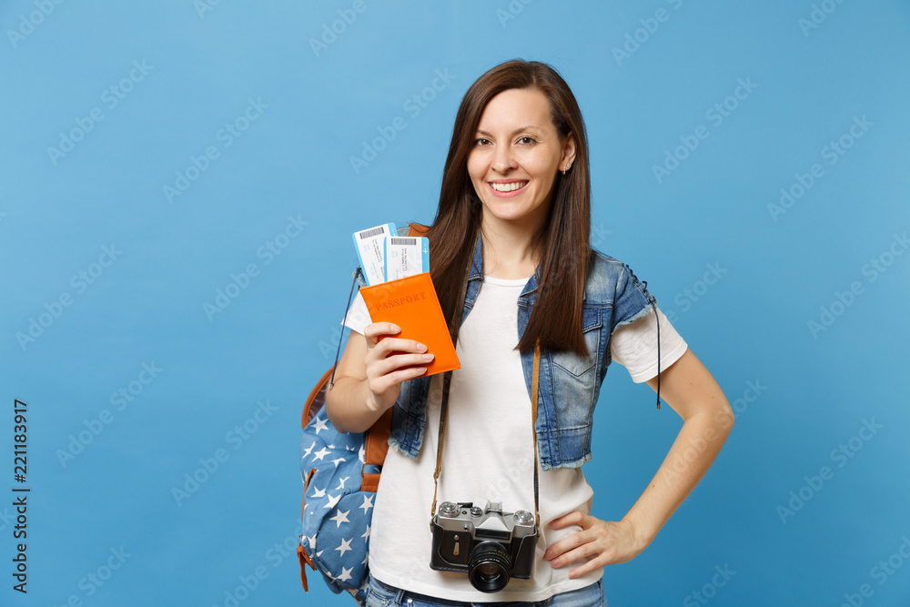Young smiling woman student with backpack and retro vintage photo camera on neck holding passport boarding pass tickets isolated on blue background. Education in university abroad. Air travel flight. Young smiling woman student with backpack and retro vintage photo camera on neck holding passport boarding pass tickets isolated on blue background. Education in university abroad. Air travel flight.