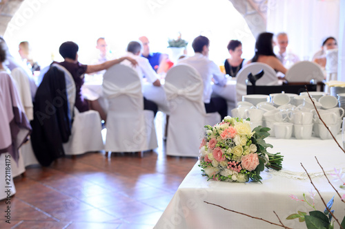 Bukiet ślubny na sali weselnej z gośćmi.