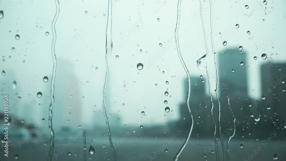 Defocused city skyscrapers behind rainy window