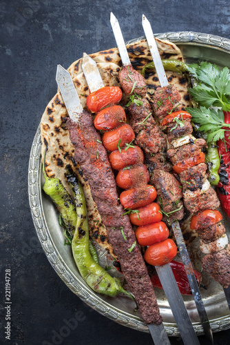 Traditional oriental adana kebap and shashlik skewer with tomato and flatbread as top view on a plate