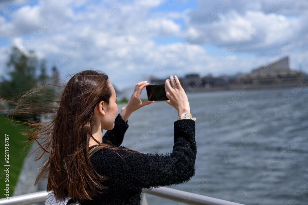 young woman on the waterfront taking pictures of the city landscape young woman on the waterfront taking pictures of the city landscape