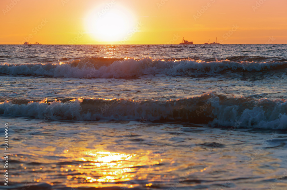 Obraz premium Sunset over the sea. Reflection of sunlight in the sea waves. Red sky in the rays of the sunset.