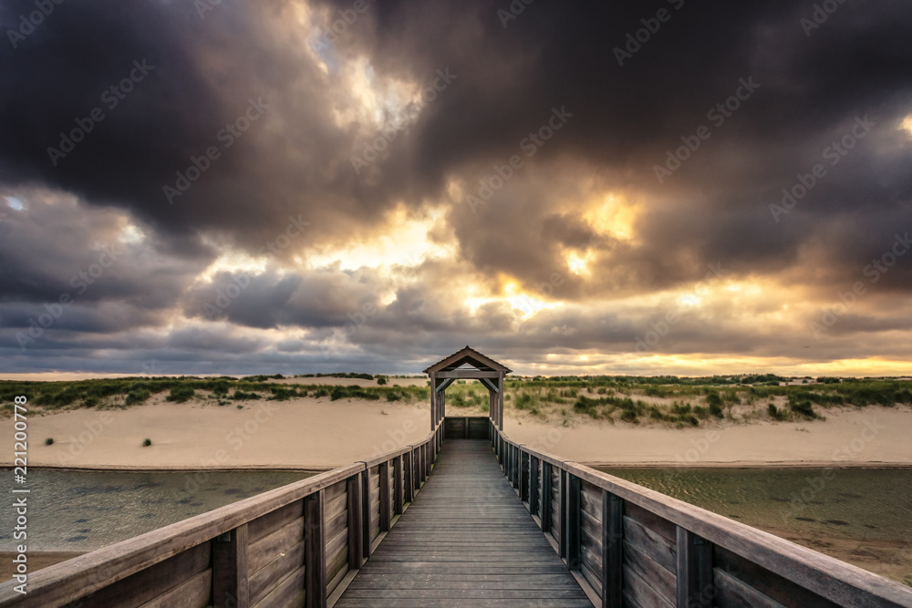 Architecture and art along the Dutch coast with beautiful sunset and threatening clouds along the beach and the dunes