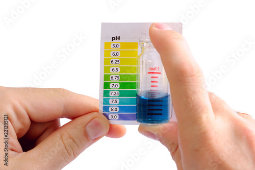Testing water pH at home. Man determining water pH by comparing the color of liquid in testing vial with attached color scale. Water is alkaline