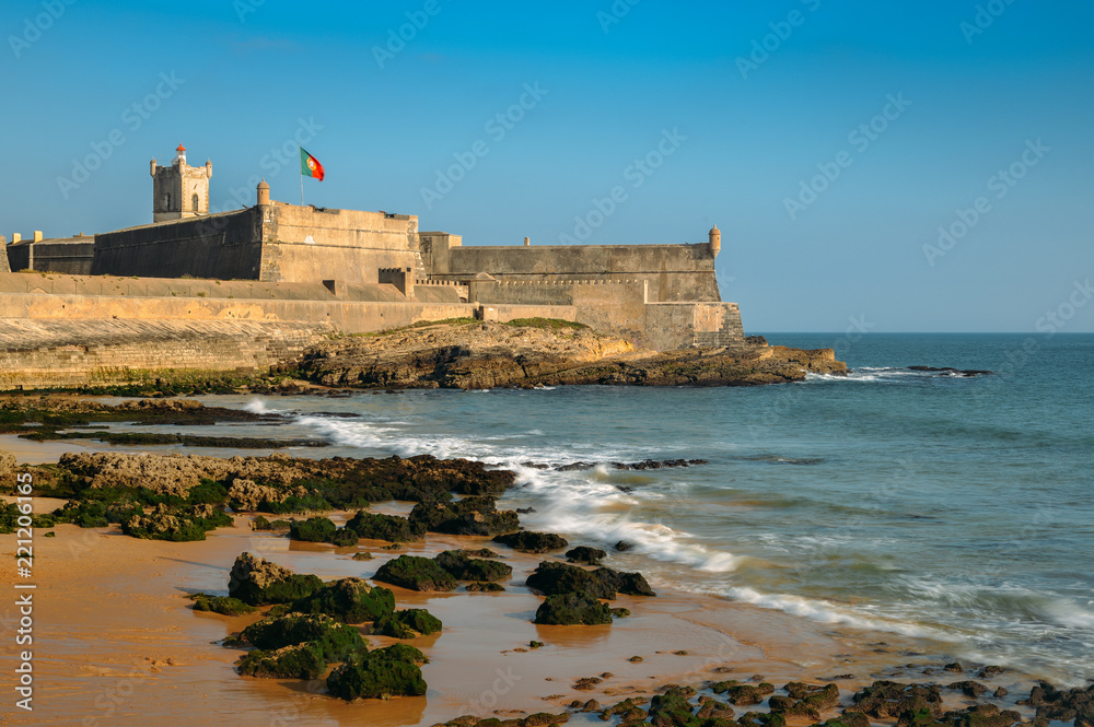 Waves crashing near the 16th Century Saint Julian Fortress at Carcavelos beach near Lisbon, Portugal