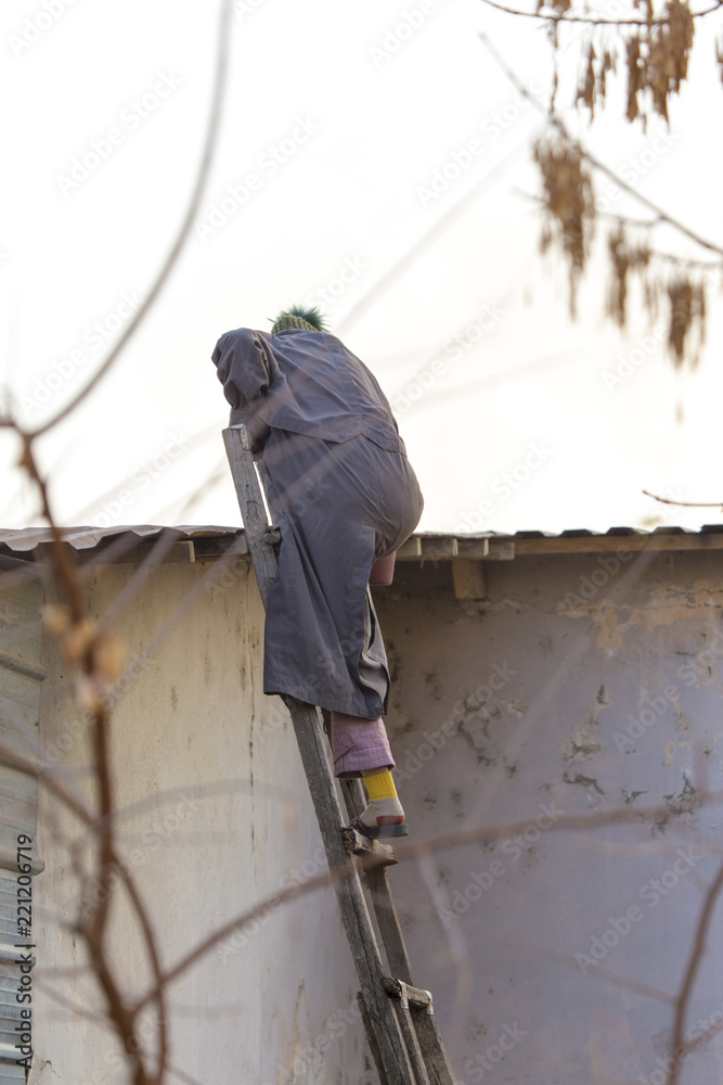 a man descends from the roof of the house, an old wooden staircase a man descends from the roof of the house, an old wooden staircase