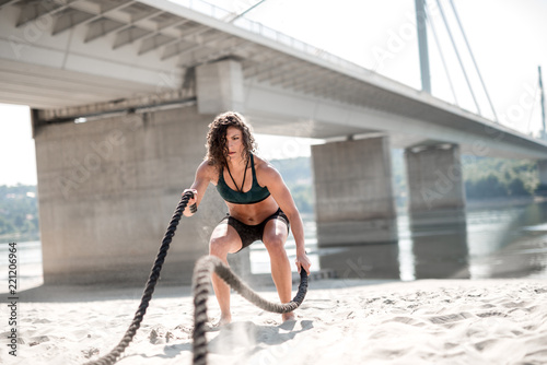 Strong woman exercising with battle ropes