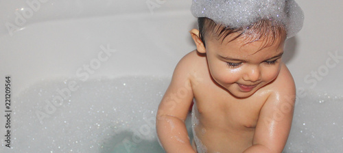 Baby boy taking a bath fith a lot of foam photo