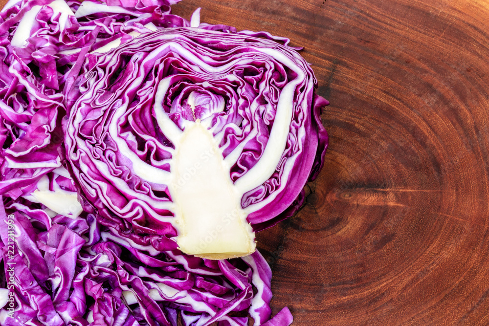Obraz premium cut purple cabbage, one whole half and another chopped on wooden board