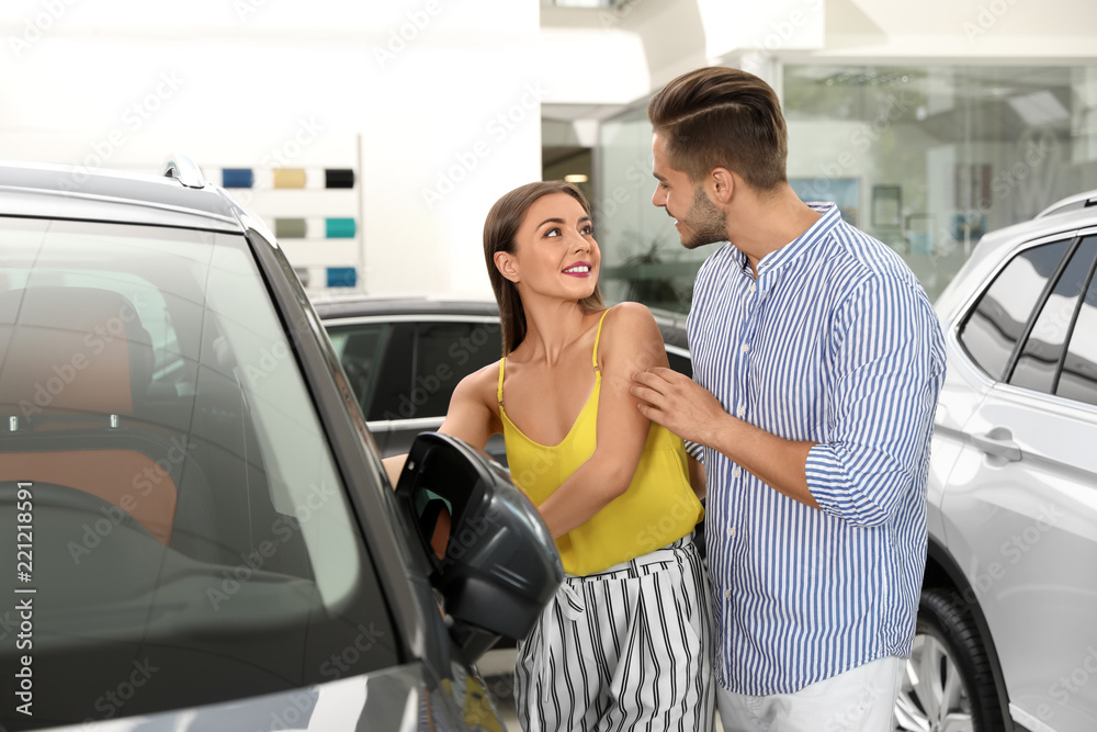 Young couple choosing new car in salon Young couple choosing new car in salon