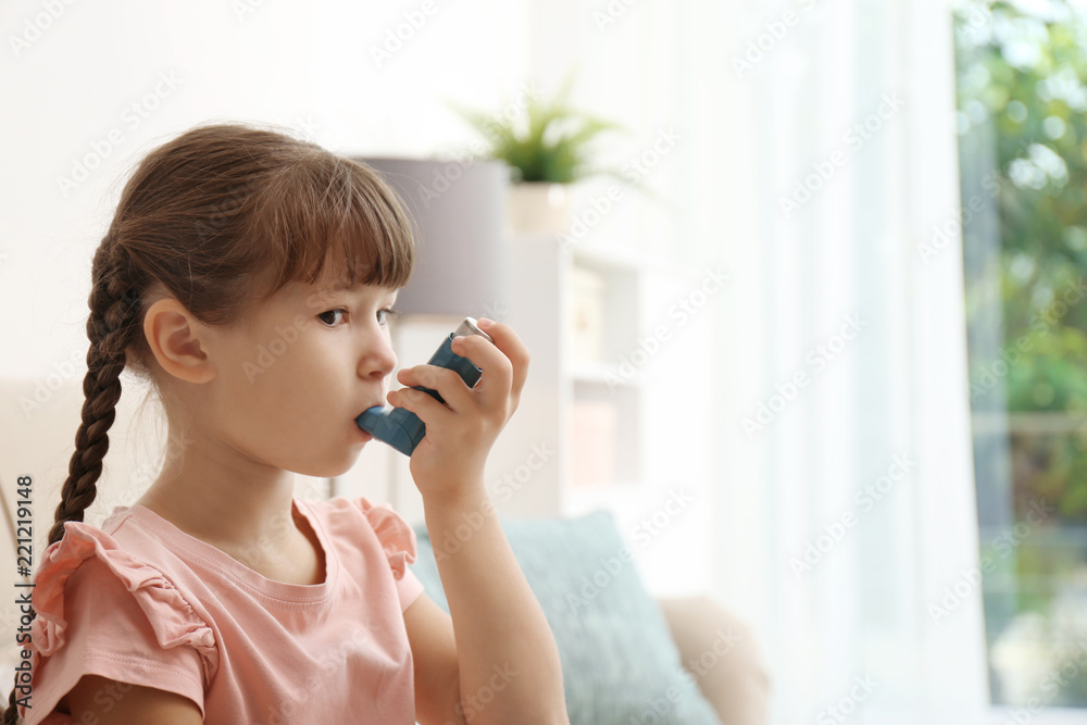 Little girl using asthma inhaler on blurred background Little girl using asthma inhaler on blurred background