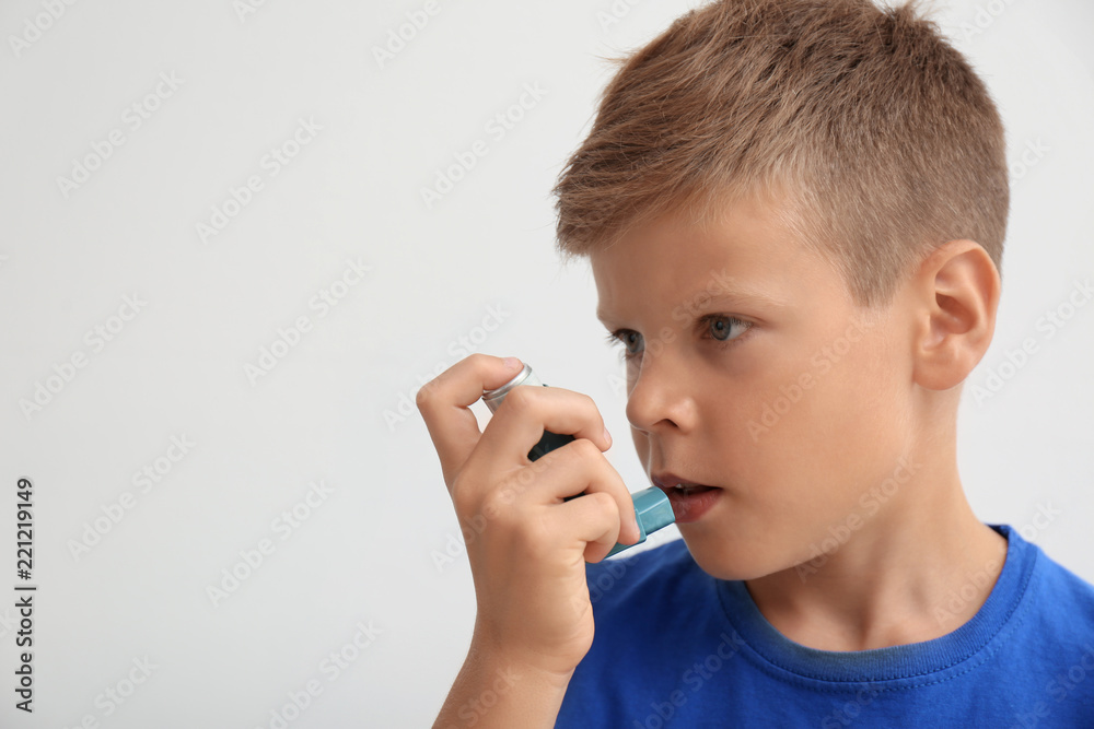 Little boy using asthma inhaler on light background Little boy using asthma inhaler on light background