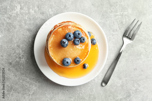 Plate with pancakes and berries on grey background, top view