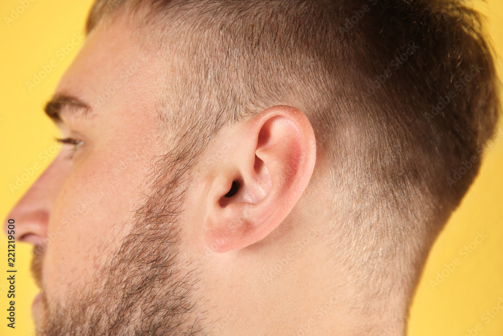 Young man on color background, closeup. Hearing problem Young man on color background, closeup. Hearing problem