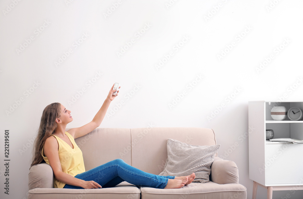 Young woman with air conditioner remote at home