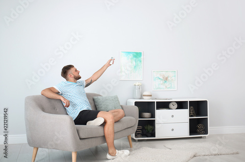 Young man with air conditioner remote at home