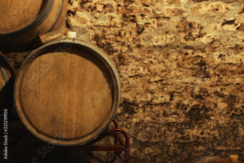 Wooden wine barrels near stone wall with space for text