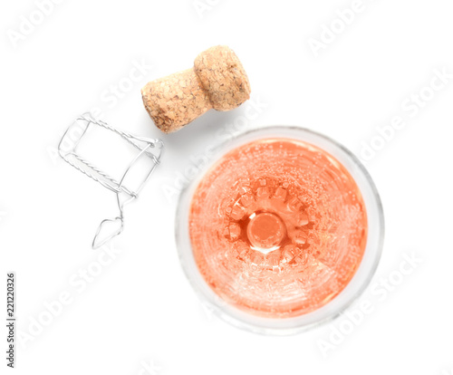 Glass of rose champagne and cork plug on white background, top view