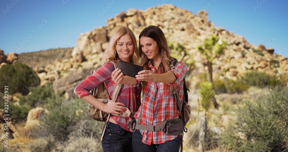 Couple of pretty young female hikers taking selfies together in desert setting