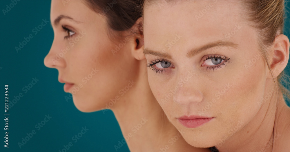 Pretty young white ladies posing with seriousness on teal background Pretty young white ladies posing with seriousness on teal background