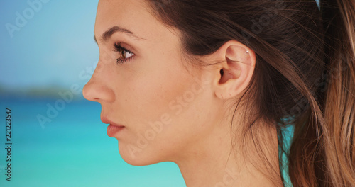 Profile of good-looking white woman standing outside by tropical beach