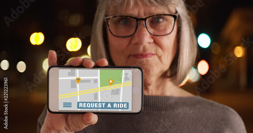 Old woman showing phone screen to camera with rideshare application open photo