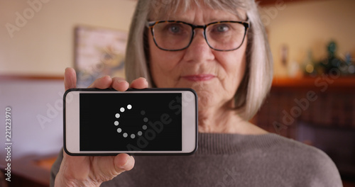 Mature Caucasian lady holding phone up to camera to show loading icon 