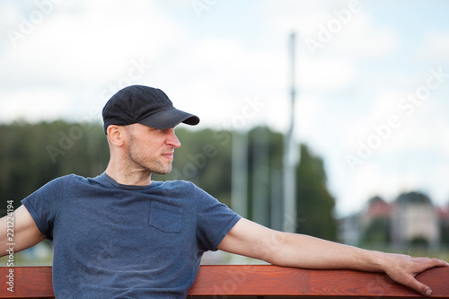 portrait of a young brutal man with a bristle resting on a bench outdoors