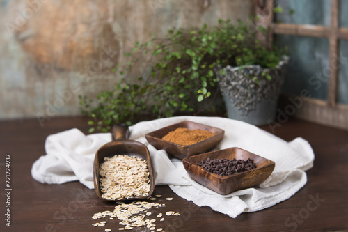 Raw Oatmeal in Wood Scoop; Coconut Brown Sugar and Mini Chocolate Chips in Wood Bowls; Wood Table photo