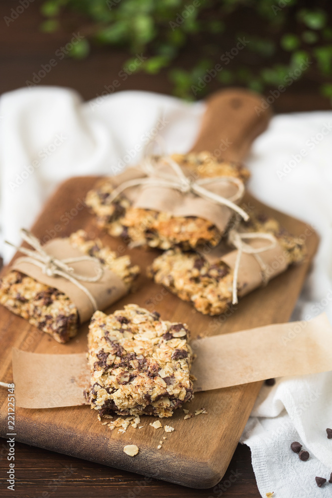 Homemade Chewy Granola Bars Wrapped in Parchment Paper and String on a Wood Cutting Board on Wood Table