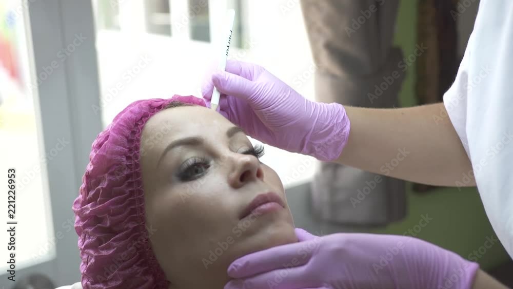 Beautician marking face for cosmetic injection in medical clinic. Woman in beauty clinic. Face care and anti aging procedure for young and beautiful skin. Beautician marking face for cosmetic injection in medical clinic. Woman in beauty clinic. Face care and anti aging procedure for young and beautiful skin.