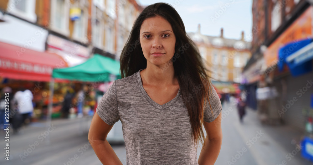 Portrait of Millennial woman looking at camera on street in commercial district Portrait of Millennial woman looking at camera on street in commercial district