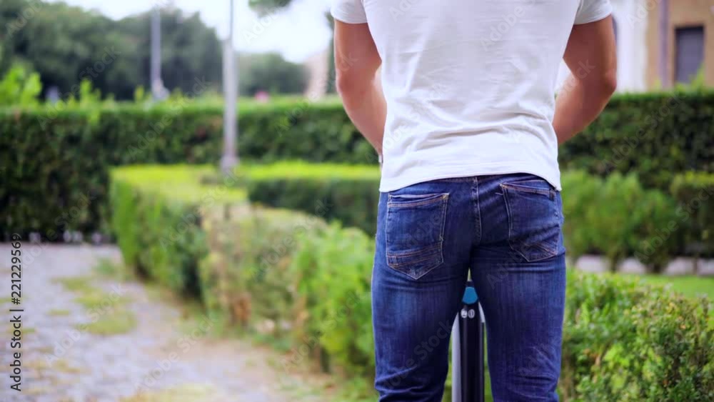 Attractive man learns to ride on gyroscooter in the city park along the narrow green streets. Modern vehicles eco-friendly transport. Shot in 4K (UHD). Attractive man learns to ride on gyroscooter in the city park along the narrow green streets. Modern vehicles eco-friendly transport. Shot in 4K (UHD).