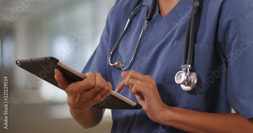 Close up of woman nurse or doctor working on tablet computer inside hospital