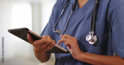 Close up of woman nurse or doctor working on tablet computer inside hospital photo