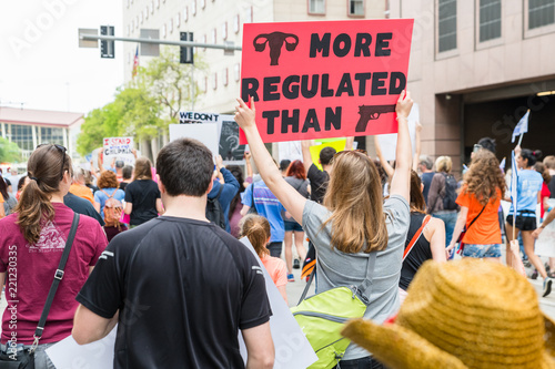 A female protester holds sign Uterus More Regulated Than Guns